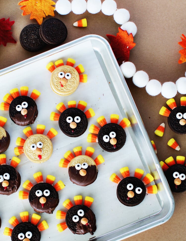 Tray of oreo cookies that have had googley eyes, butterscotch chocolate chips and candy corn added to them to represent turkey feathers and look like a turkey.