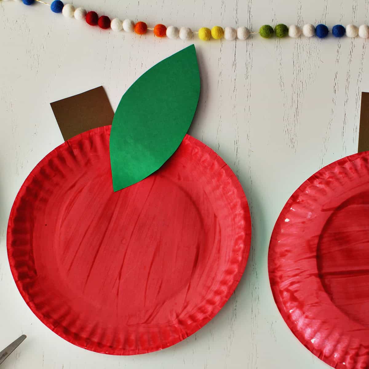 Red plate painted red with a piece of green cardstock glued on for a leaf and a brown piece for the stem of the apple.