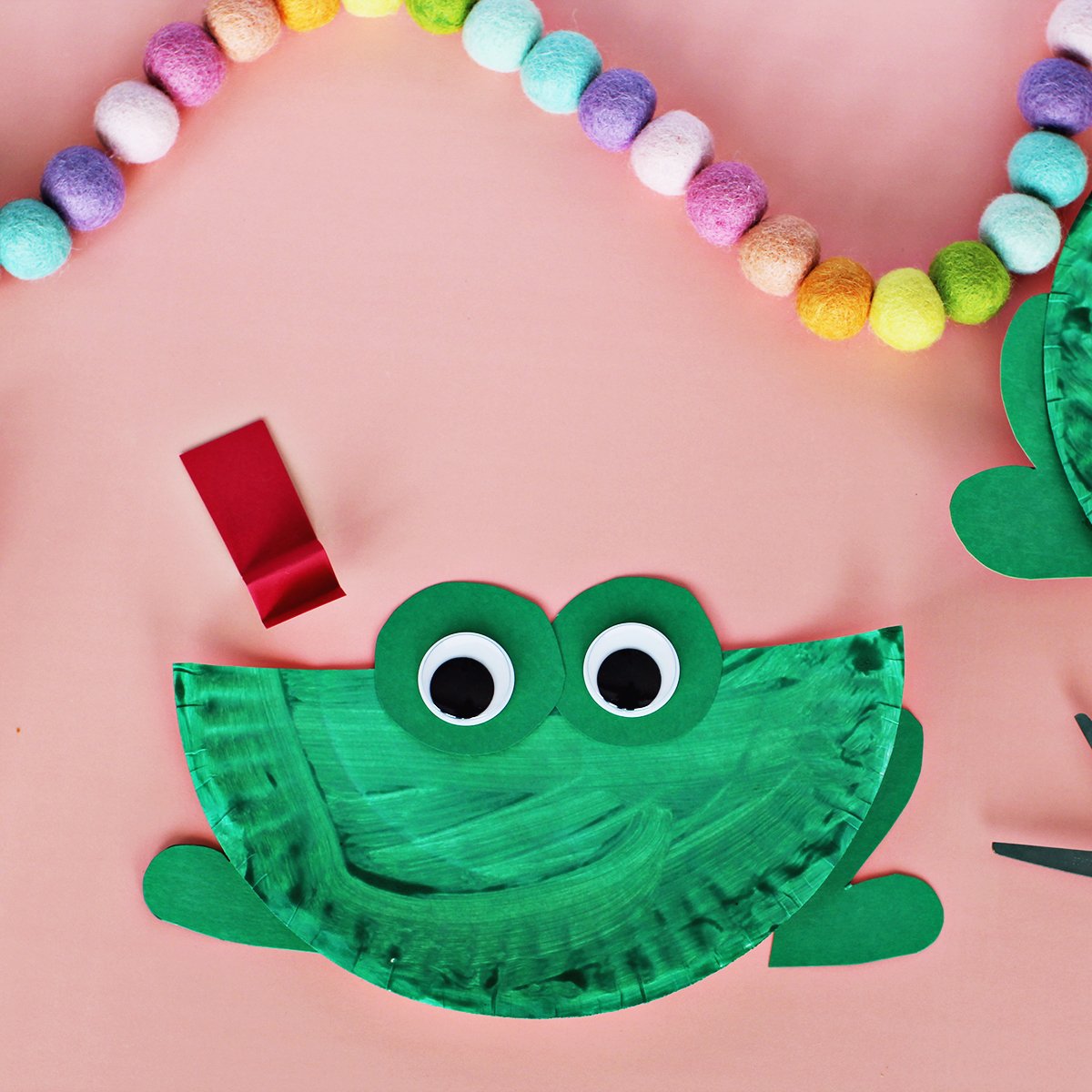 Googley eyes glued onto green paper which has been glued onto a green paper plate.