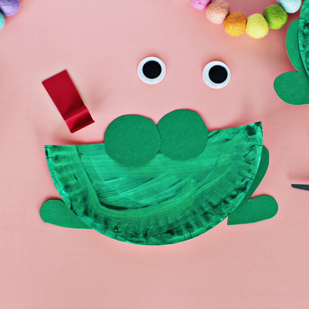 Green paper being glued onto a green paper plate.
