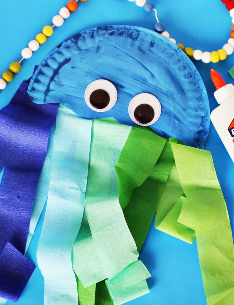 Paper plate painted blue and cut in half with streamers glued onto it to make a jelly fish craft.