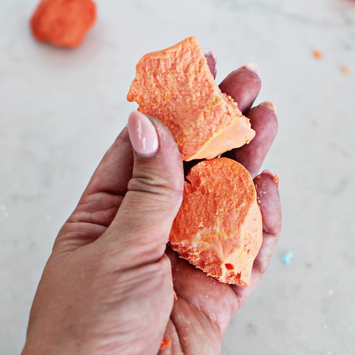 Hand holding orange cloud dough.