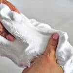 Hands pulling and stretching snow slime.