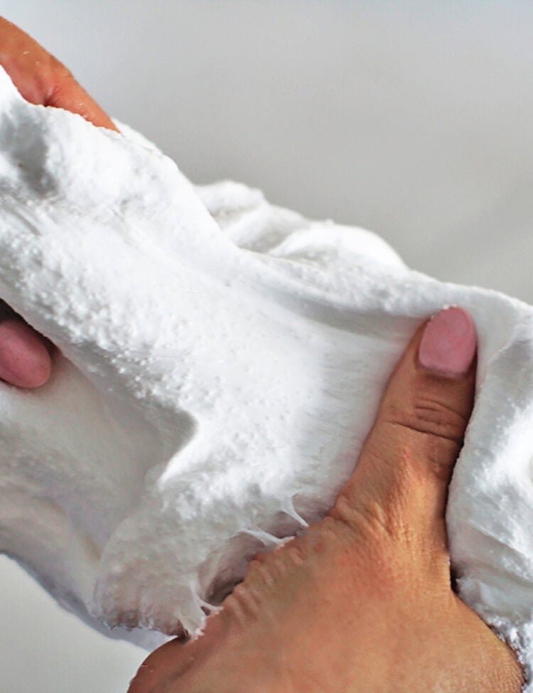Hands pulling and stretching snow slime.