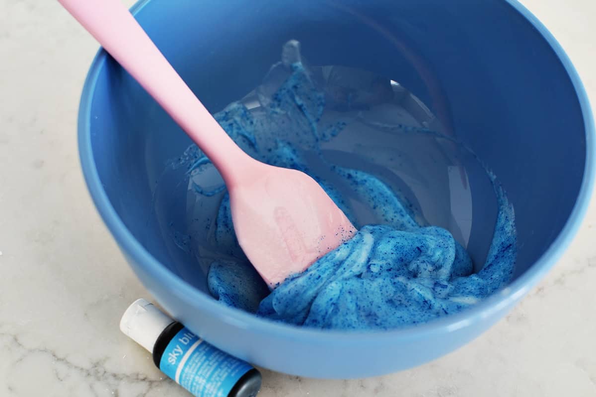Blue food coloring being mixed with conditioner to make cloud dough.