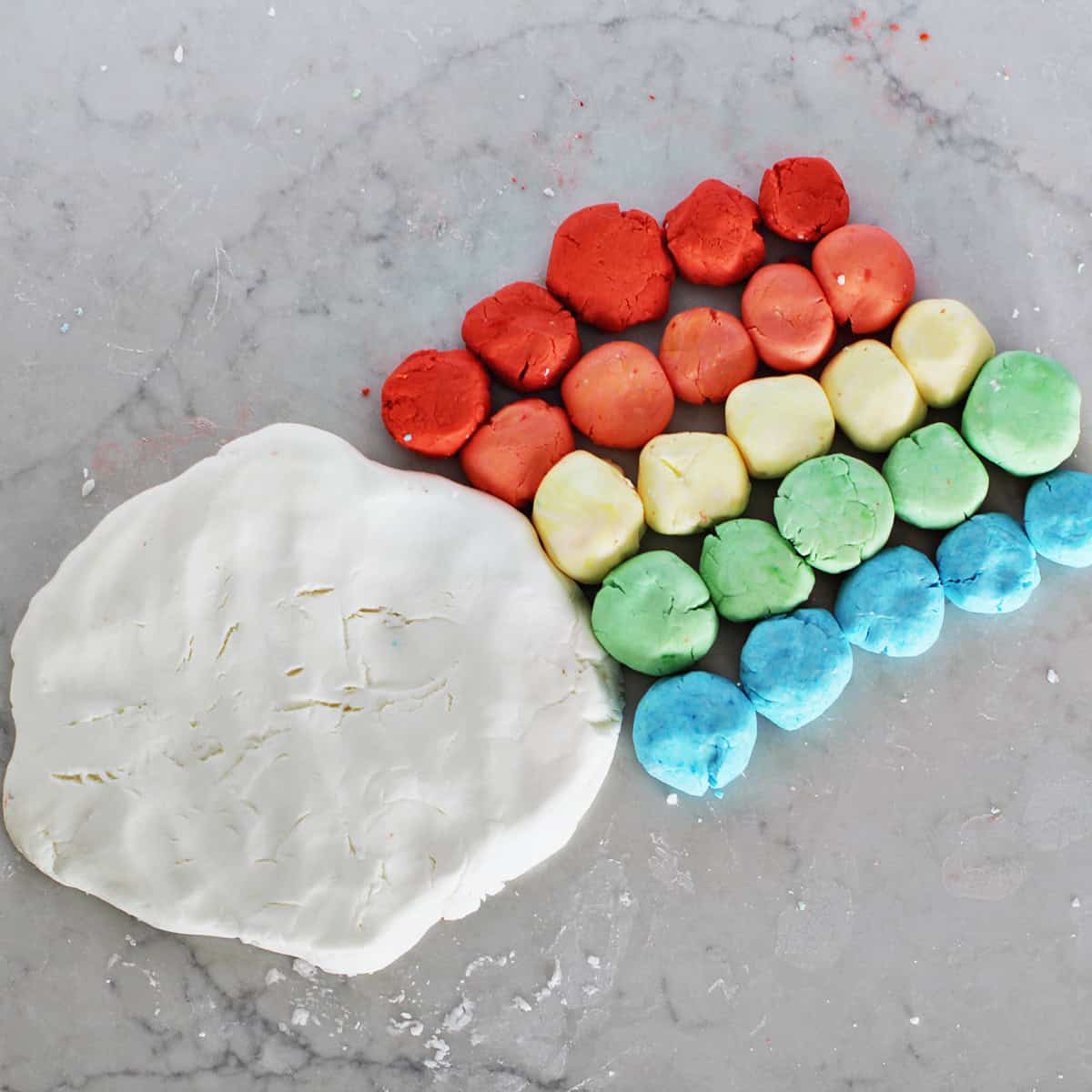 rainbow colored homemade dough next to white dough making cloud dough.