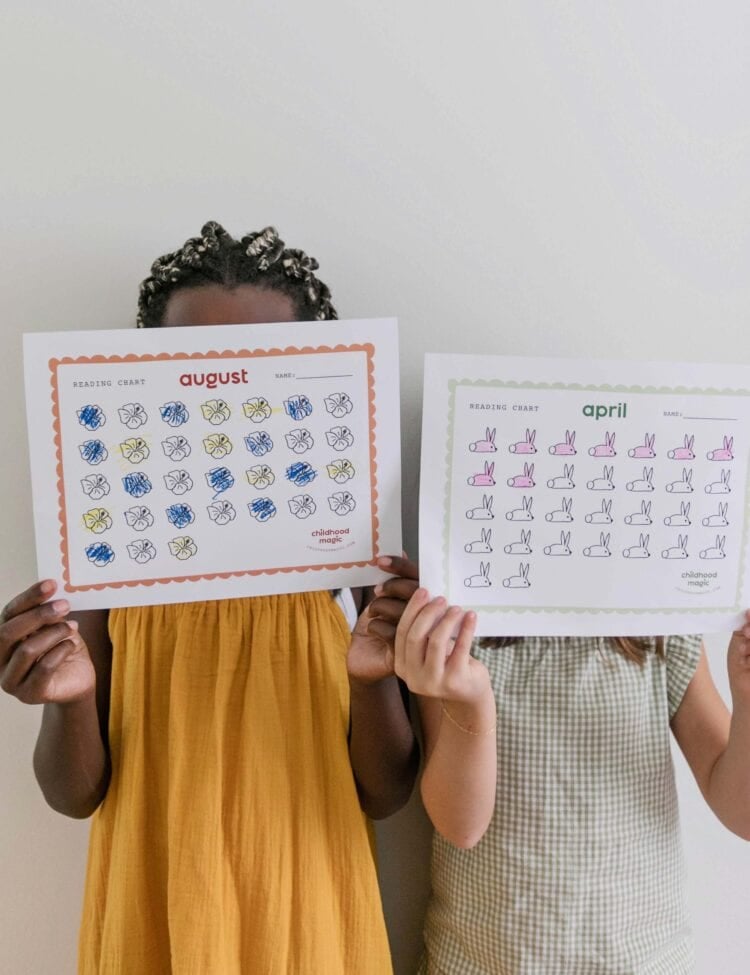 Two children holding printable reading charts.