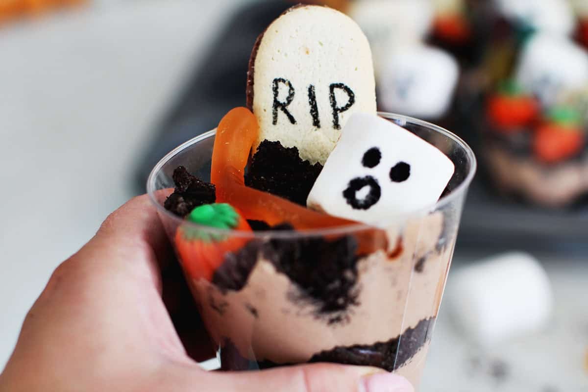 Hand holding Halloween themed dirt cup dessert.