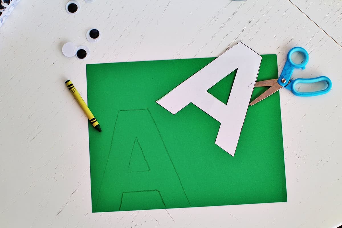 Green cardstock with a letter 'A' template being traced and cut out.