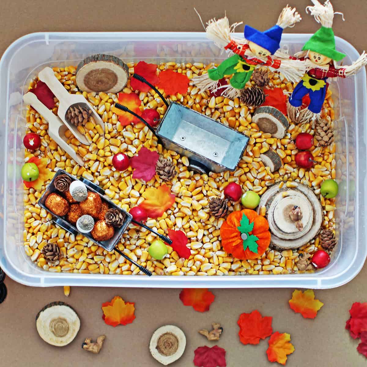 Autumn themed sensory bin filled with corn kernals and fall miniatures.