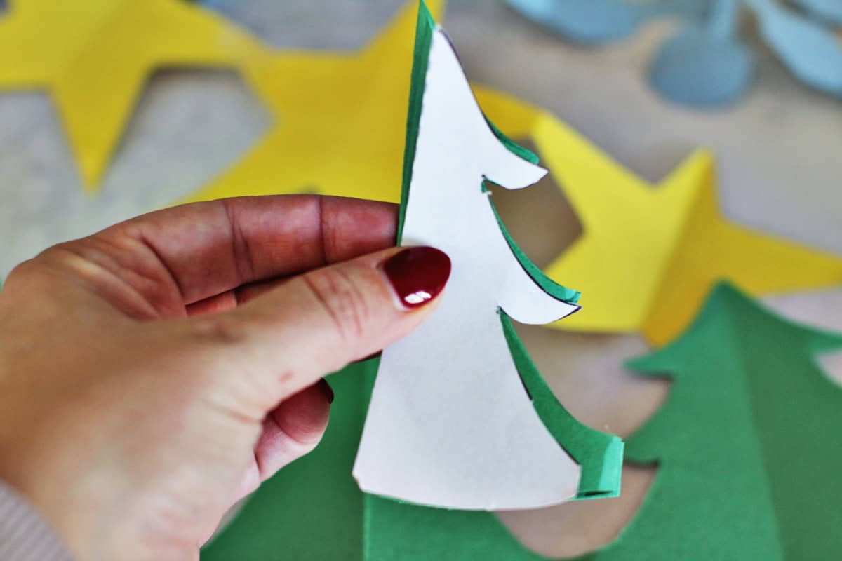 Christmas tree paper chain being cut out of green construction paper.