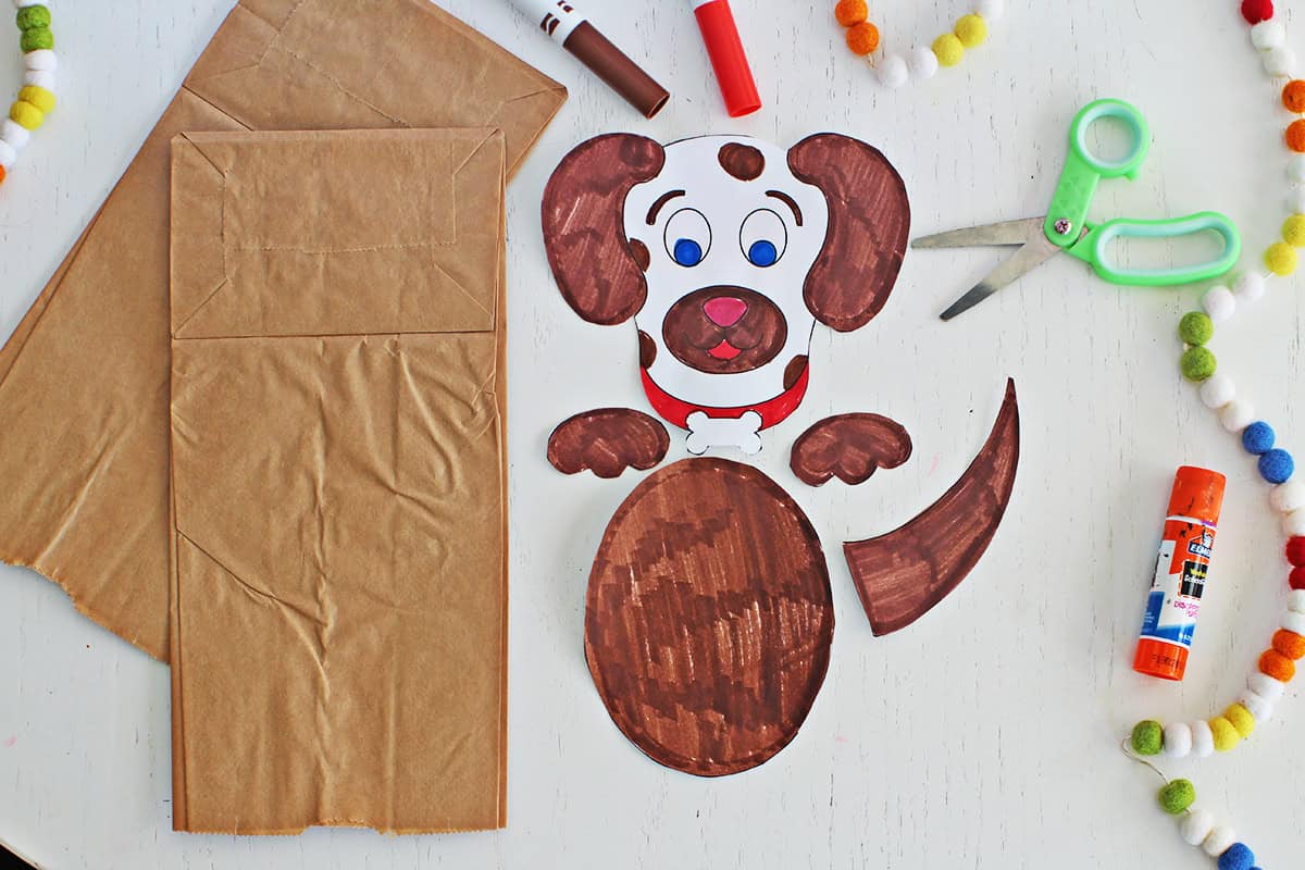 Printed pieces of a dog cut out to make a paper bag puppet.