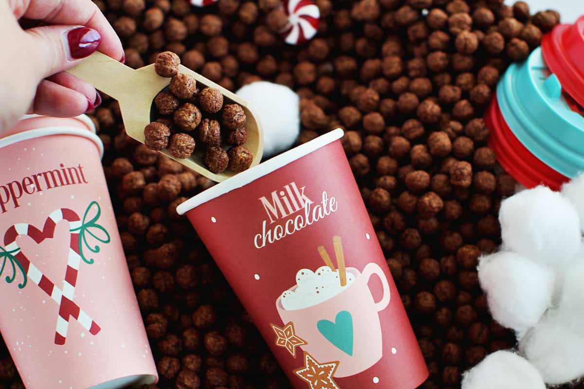 adding cocoa puffs to cup for making pretend hot cocoa.