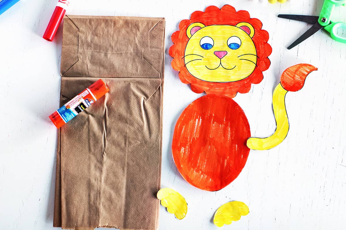 Colored and cut out lion pieces ready to glue onto a paper bag.