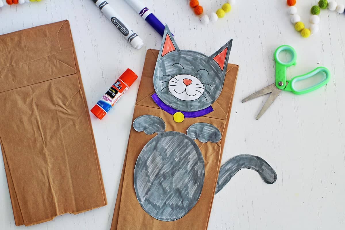 Paper bag puppet craft with a page colored in as a cat.