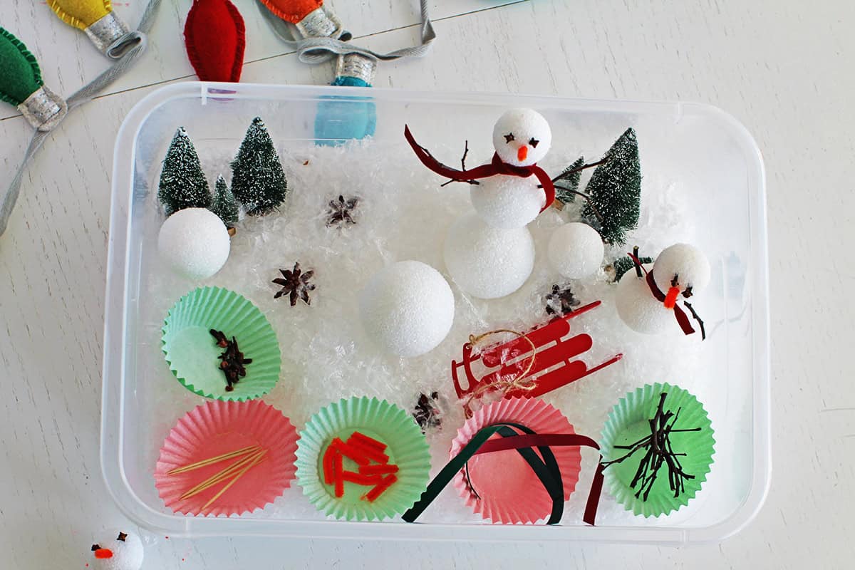 sensory bin filled with winter themed items to build a snowman.