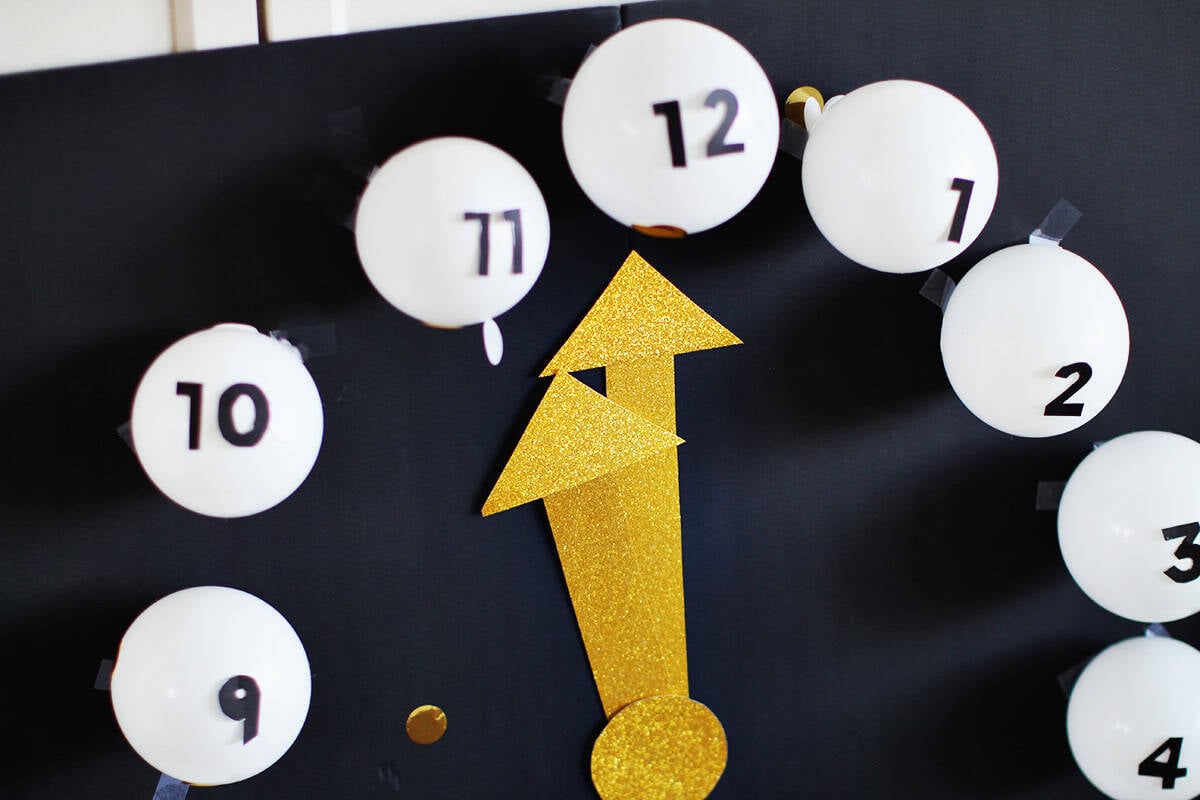 clock made from small white balloons with black cardstock numbers taped onto them.
