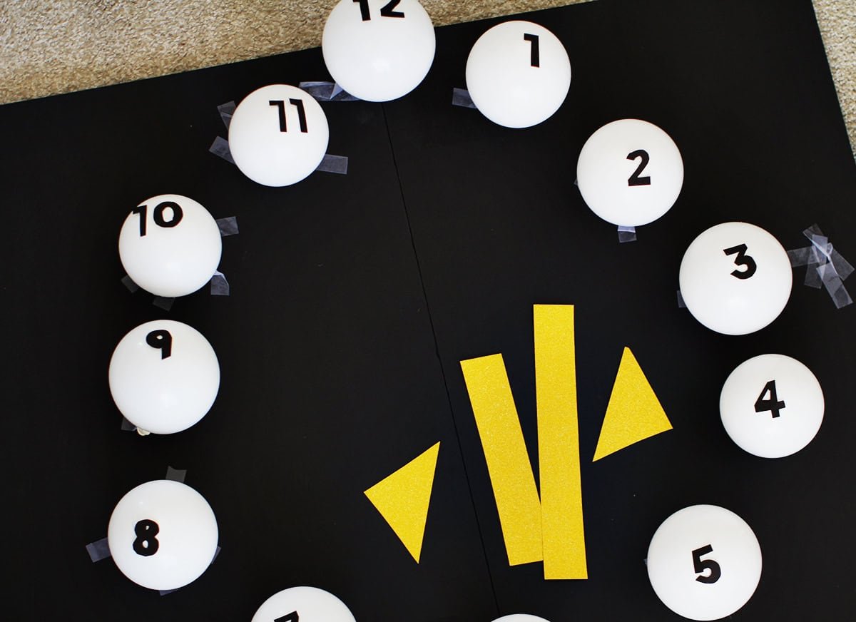 clock made from small white balloons with black cardstock numbers taped onto them.