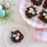 bird's nest cookies made from chow mein noodles and with candy eggs sitting on a plate.