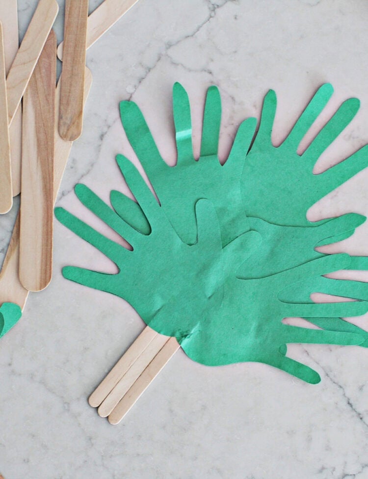 Green cut out handprints glued to popsicle sticks to make a palm branch.
