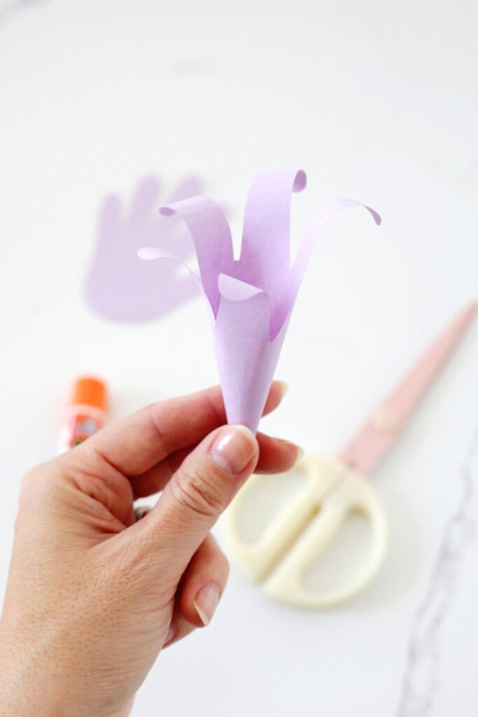 Hand holding a handprint lily shape.