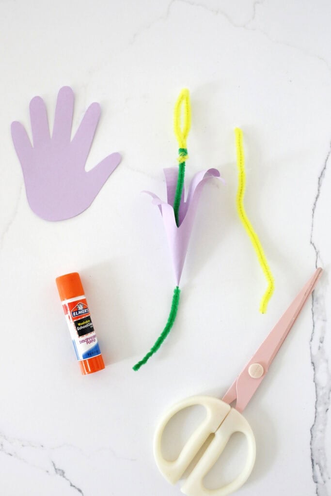 yellow and green pipe cleaner being made into a stem to make a craft flower from a handprint.