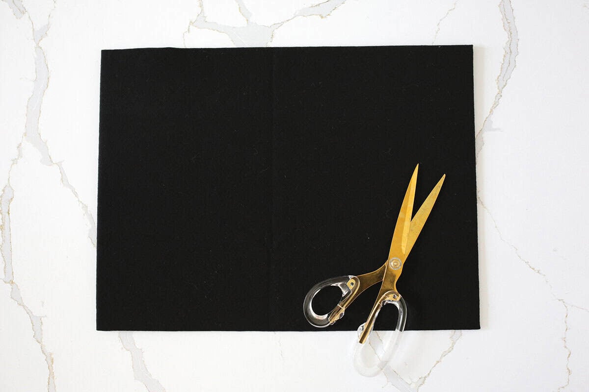 Black felt with scissors being attached to a poster board.