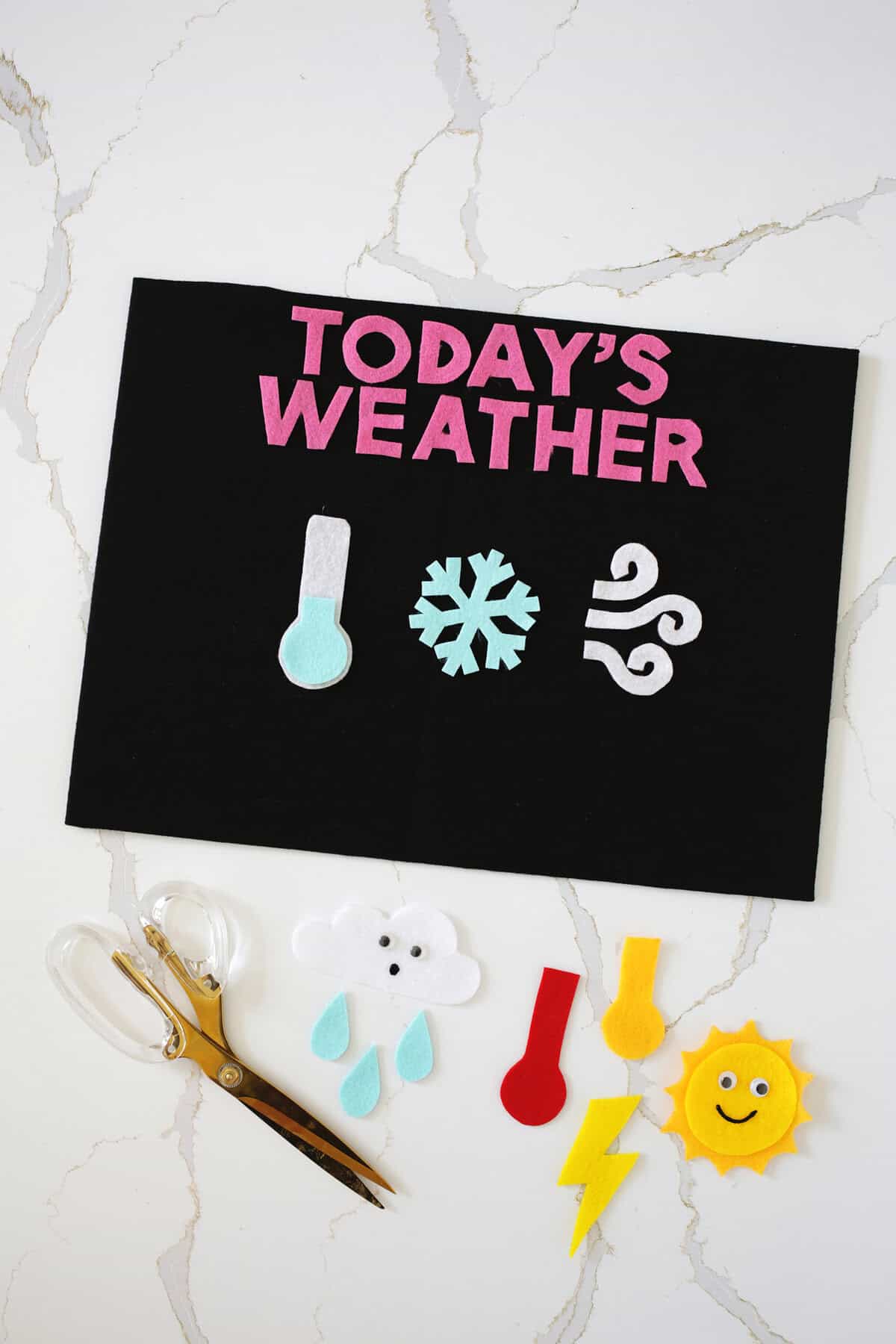 Felt weather chart craft for kids showing a cold temperature gauge, a snowflake, and a windy symbol.