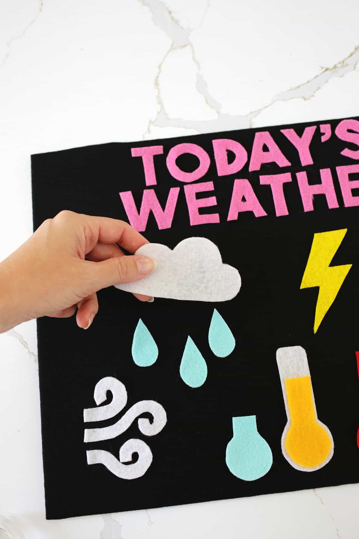 Felt cloud being moved on a felt weather board for kids.