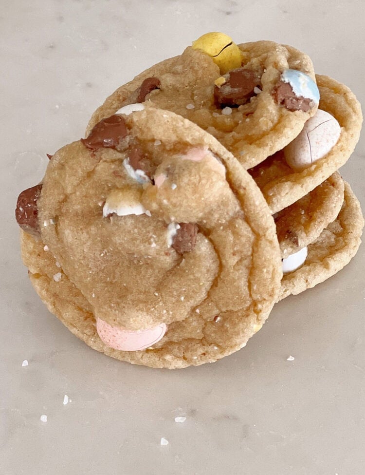 Chocolate chip cookies with cadbury eggs in them sitting on a counter.