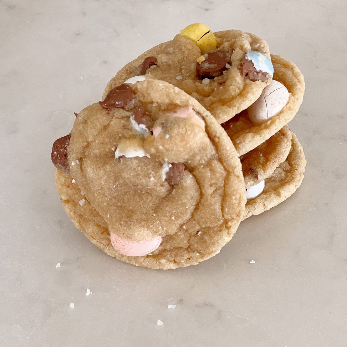 Chocolate chip cookies with cadbury eggs in them sitting on a counter.