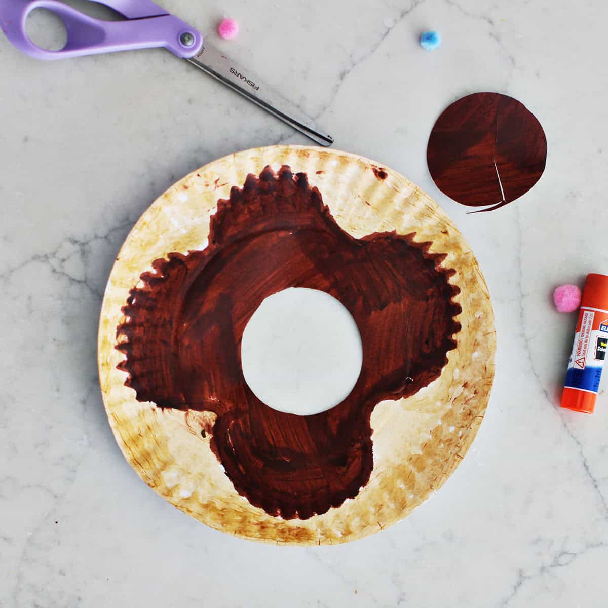 Paper plate with center cut out to make a donut.