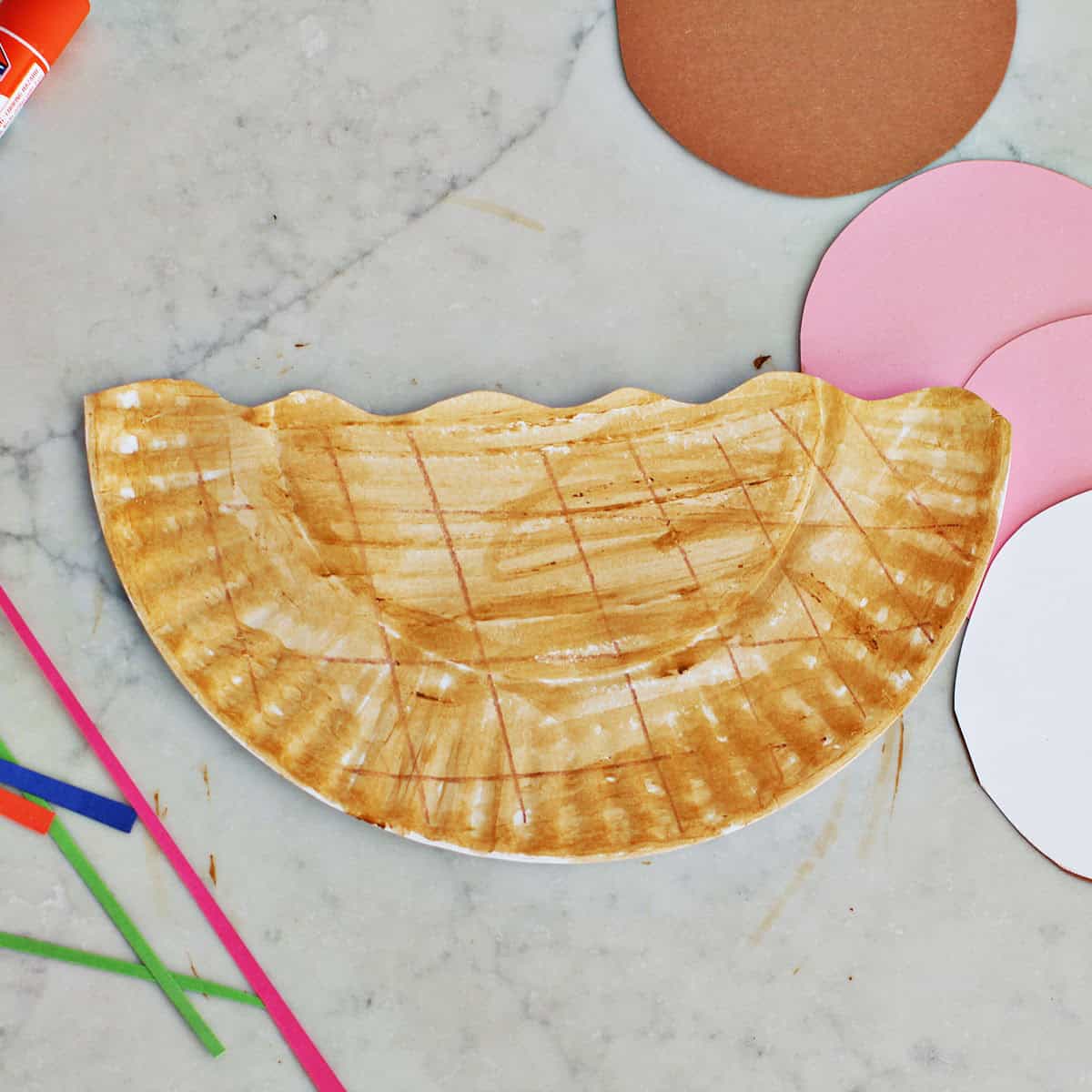 Beige painted paper plate cut in half.