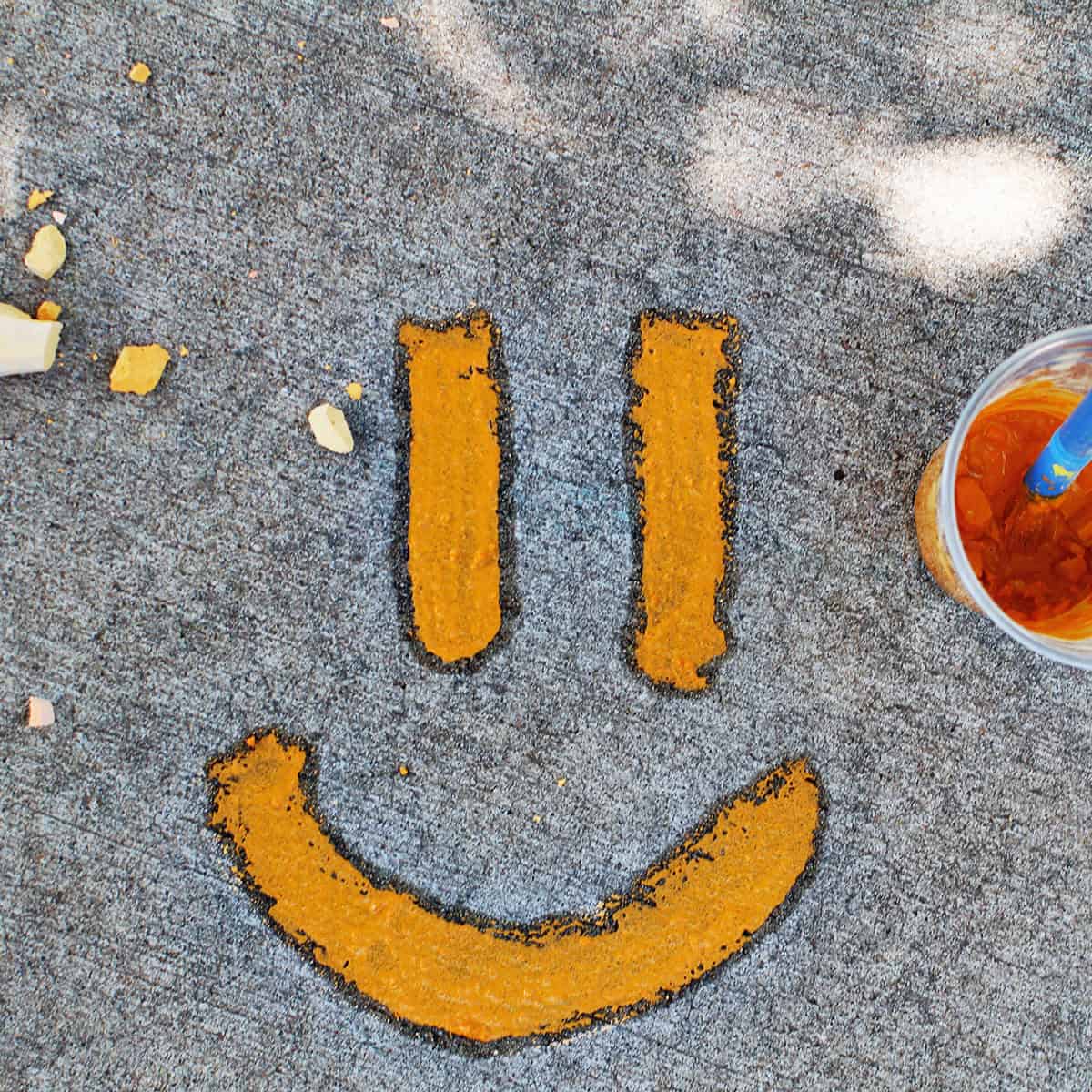 orange chalk paint on the cement in the shape of a smiley face.