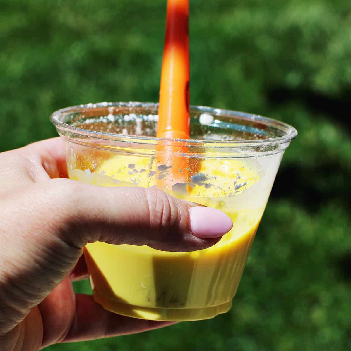Hand holding a cup of yellow chalk paint in a cup.