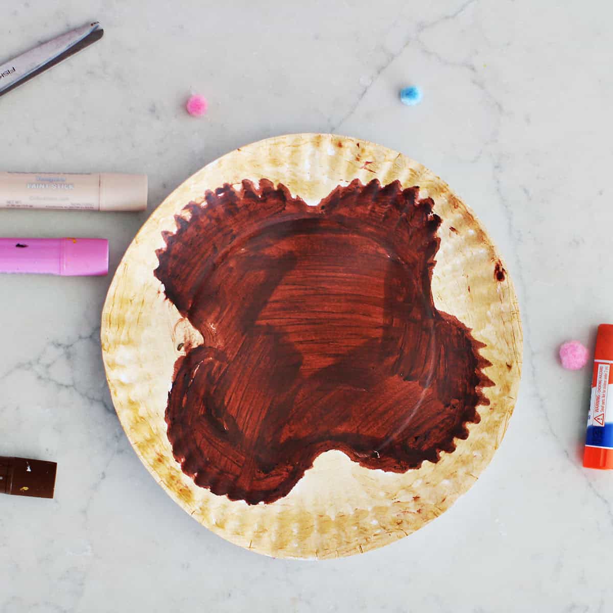 paper plate with brown and beige paint on it.