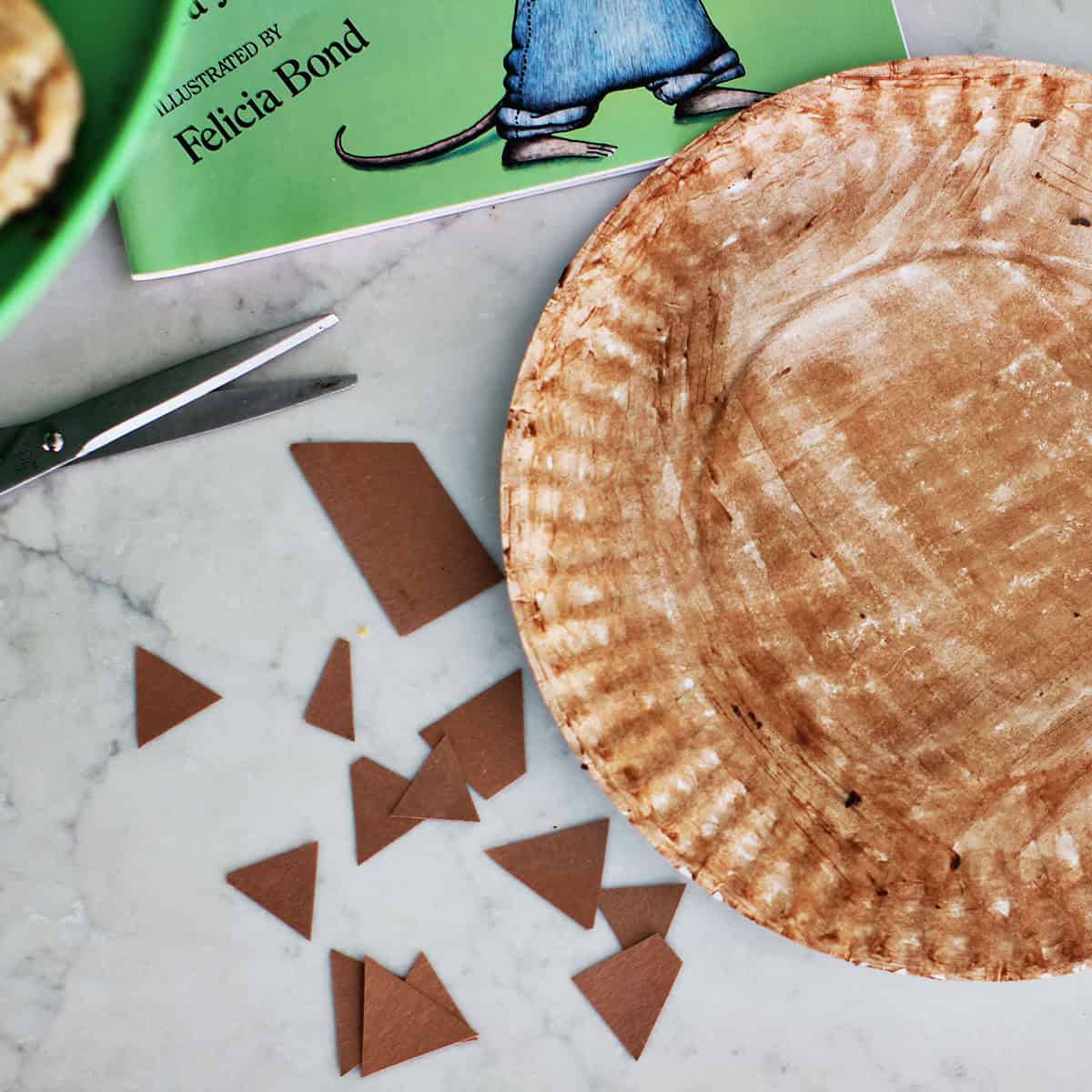Paper plate painted brown next to cut pieces of brown construction paper.