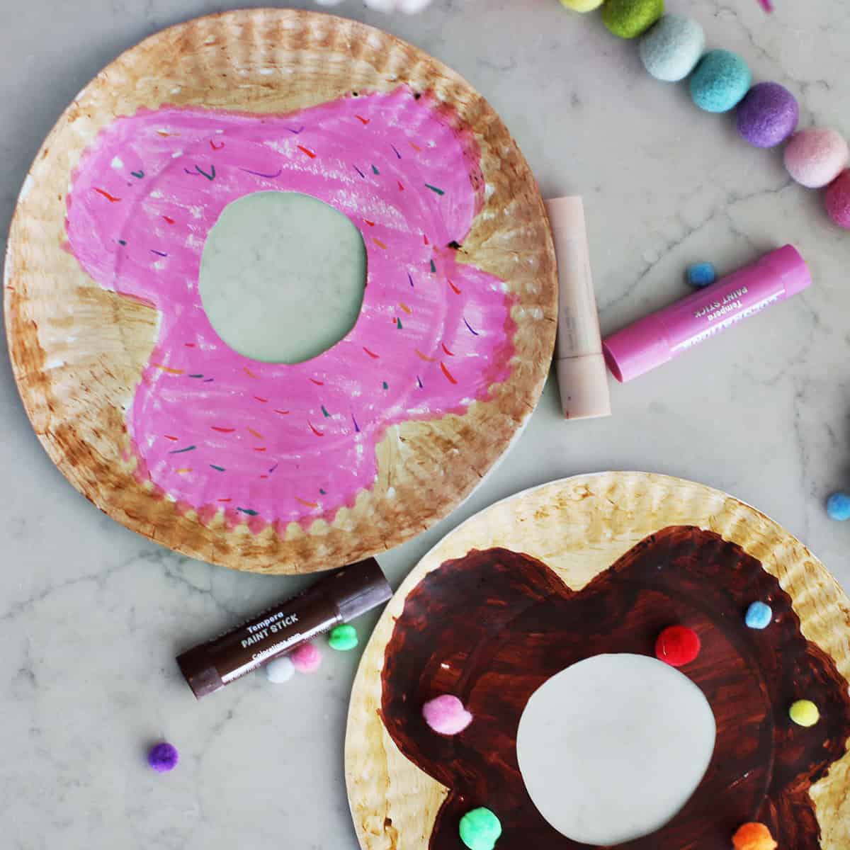 paper plates painted and decorated to look like donuts.