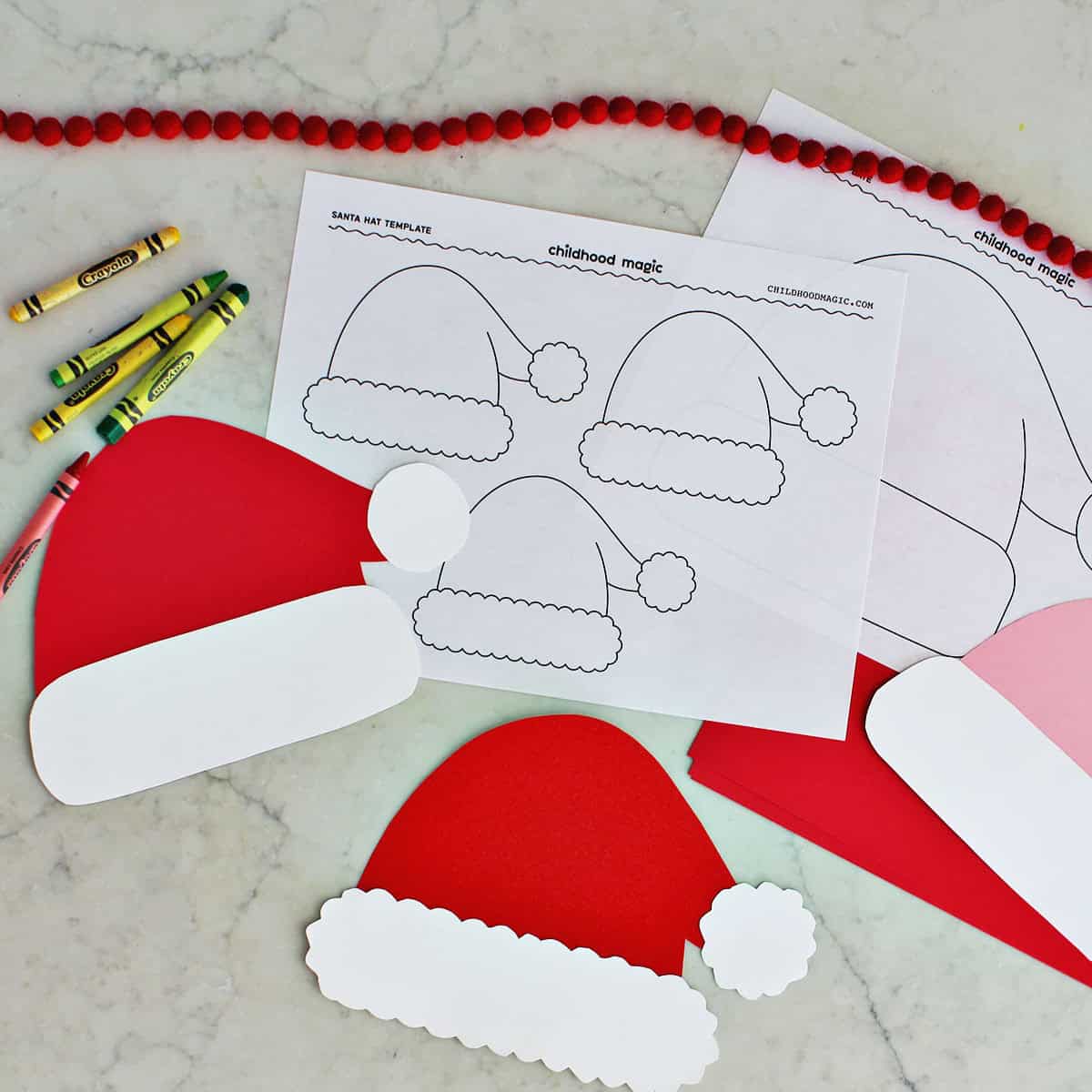 printed santa hats on a page next to three crafted cardstock santa hats.