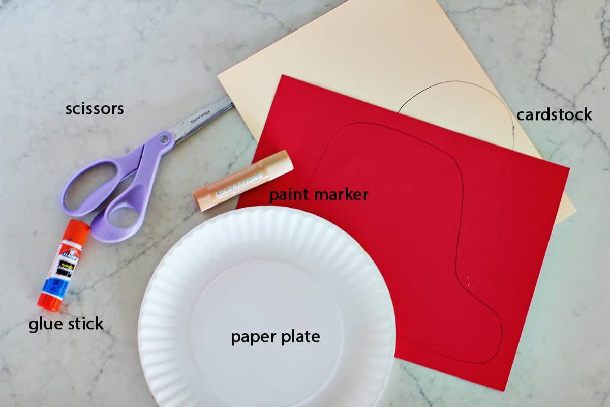 paper plate, scissors, cardstock, glue stick and paint stick on a counter.