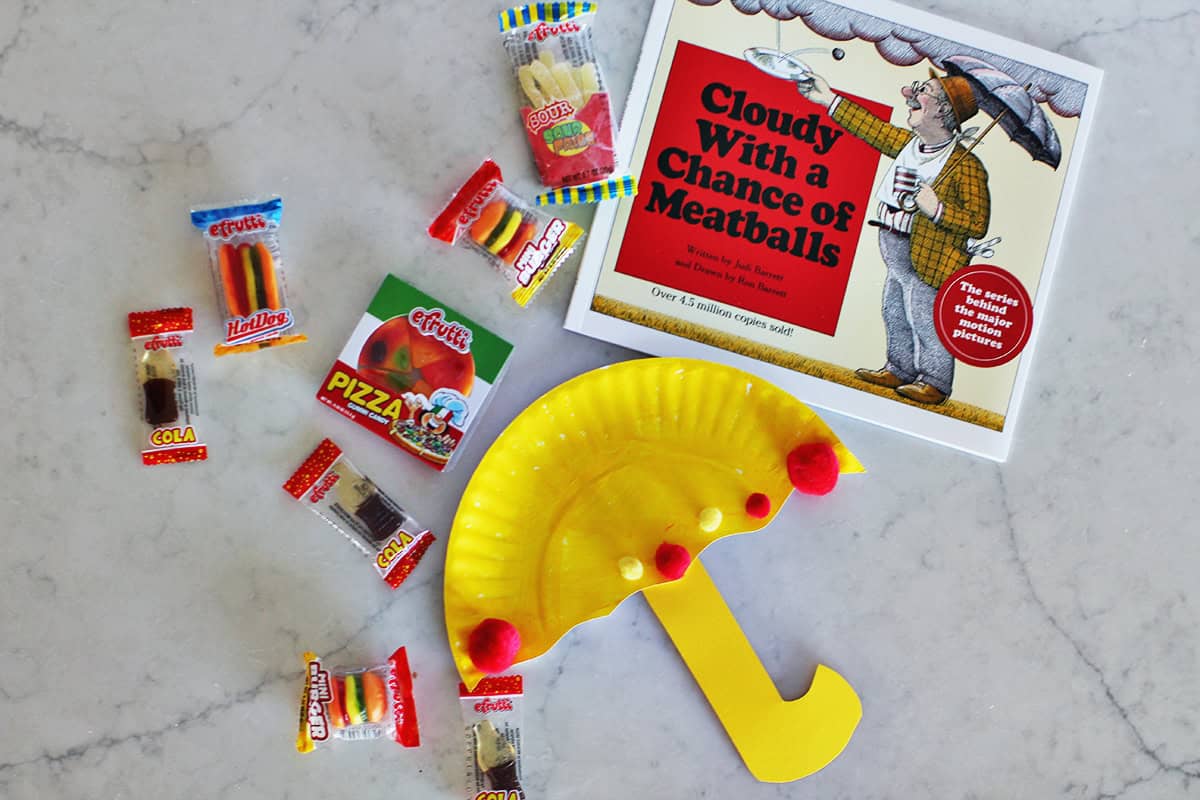paper plate umbrella craft next to gummy candy and Cloudy with a Chance of Meatballs book.