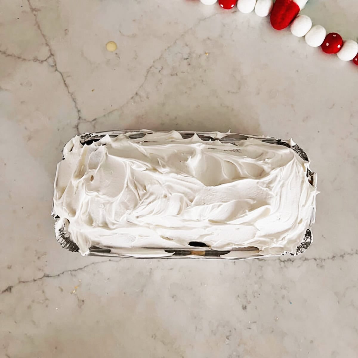 Overhead view of a pound cake covered in coolwhip.