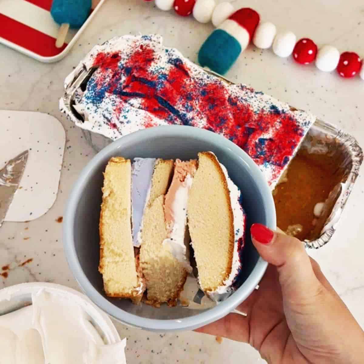 Hand holding a bowl with the finished cake in it, you can see the three layers of pound cake with ice cream inbetween each layer.