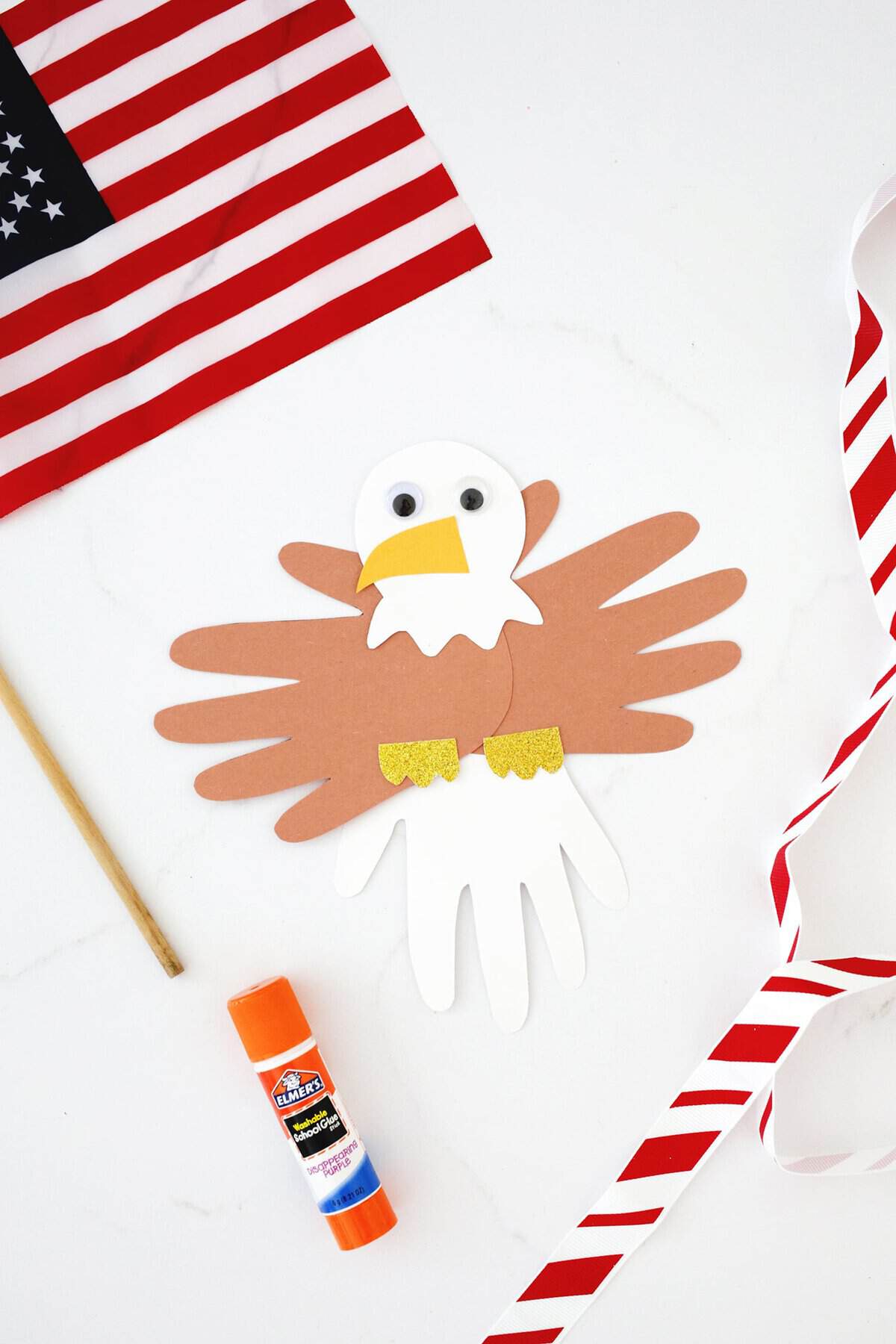 Fourth of July eagle handprint craft on a counter next to a small American flag.