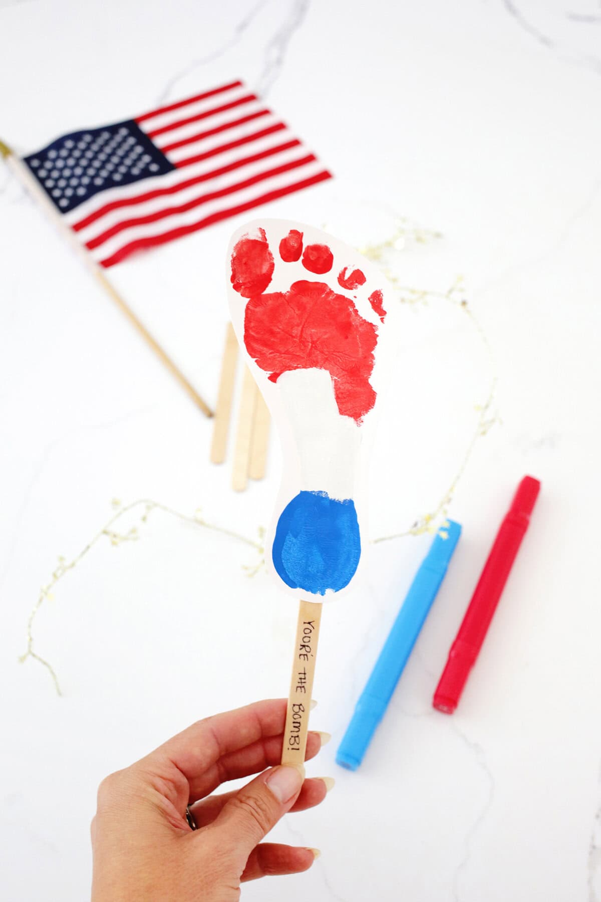 a footprint print mae with red, white and blue paint to look like a popsicle glued onto a craft stick.