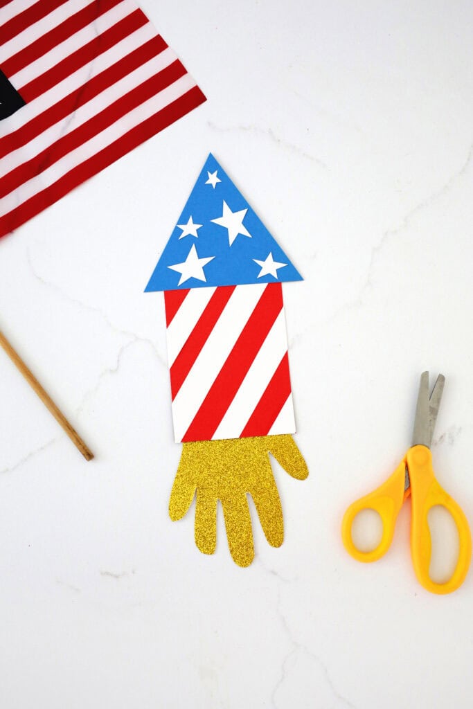Pieces of cardstock glued together to look like a rocket including a gold cardstock handprint.
