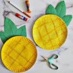 Two paper plates crafted to look like pineapples on a counter.