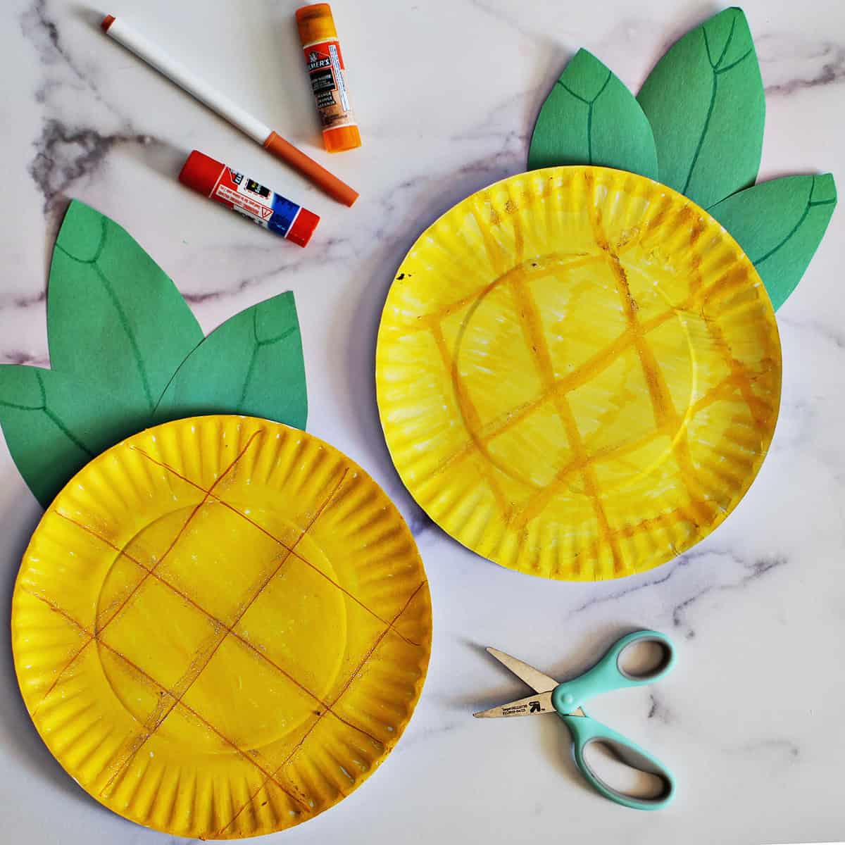 Two paper plates crafted to look like pineapples on a counter.