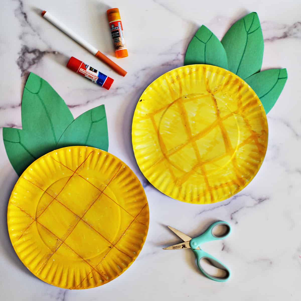 Two paper plates crafted to look like pineapples on a counter.