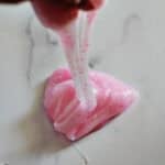 Hand pulling pink glitter slime off a counter.
